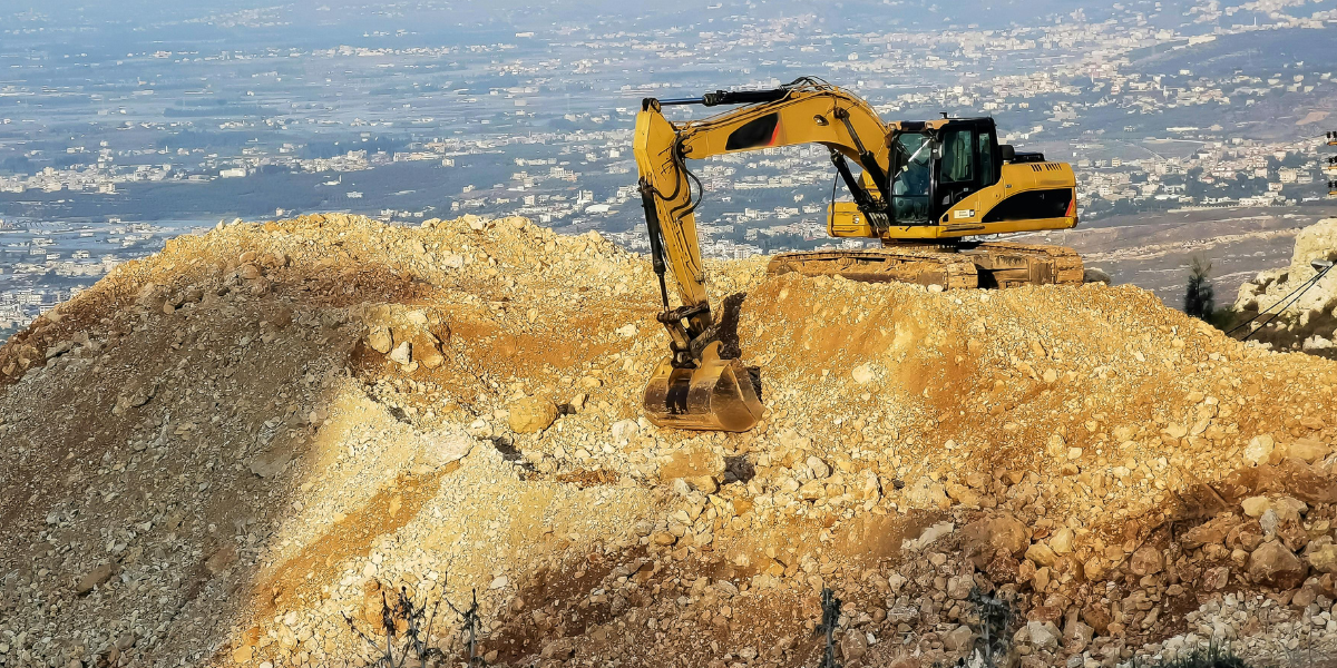 Excavator working on a rocky hilltop during a construction project